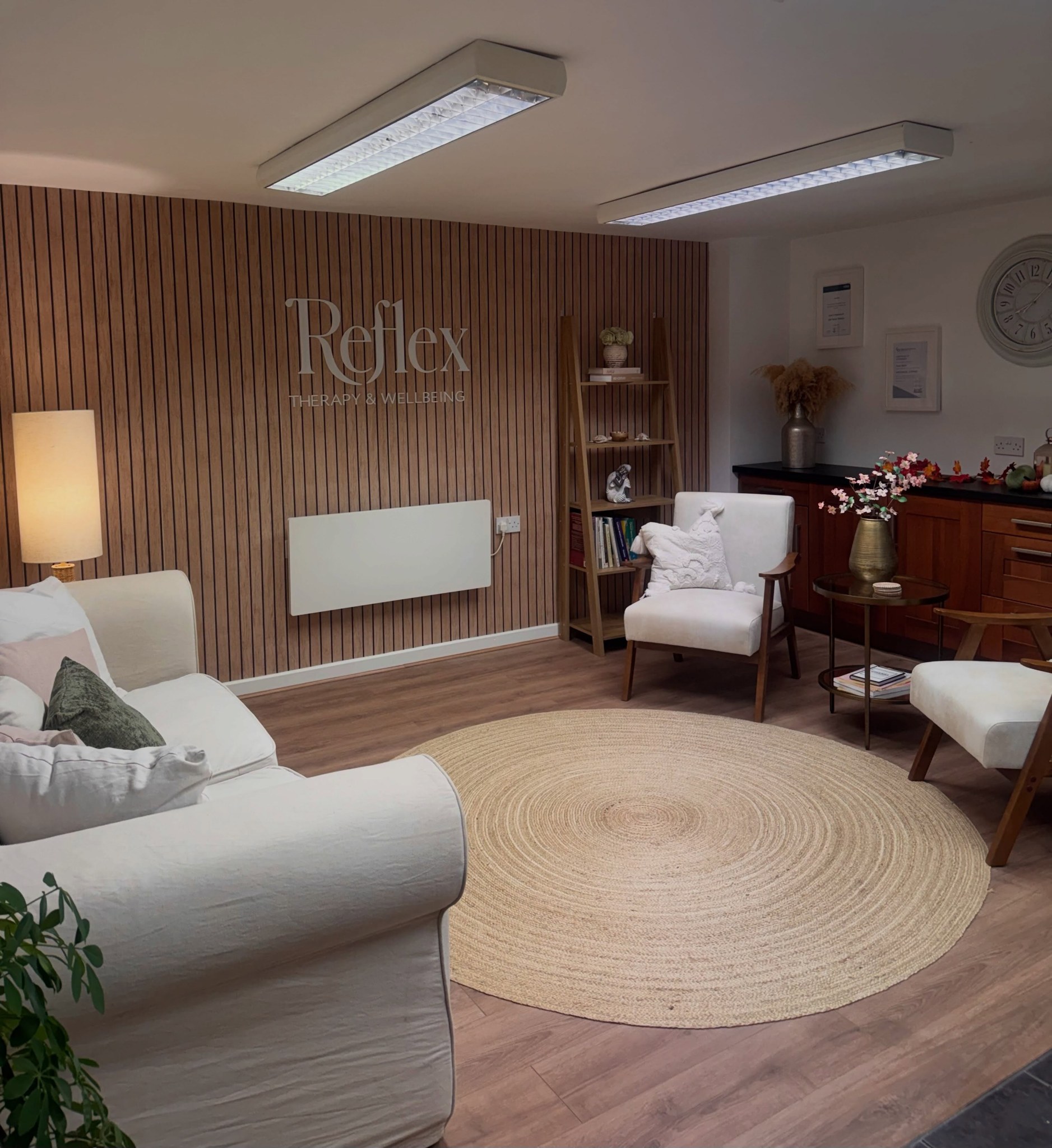 The seating area at Top Barn with cream armchairs, a jute rug and the Reflex lettering on the slatted wall