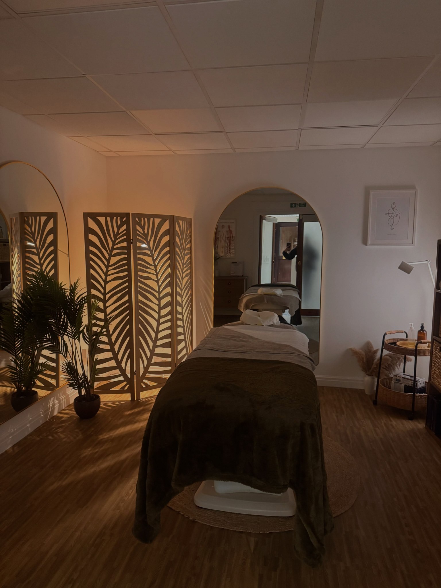 The new treatment room at Top Barn, with a massage couch, warm lamp light and palm-leaf screens